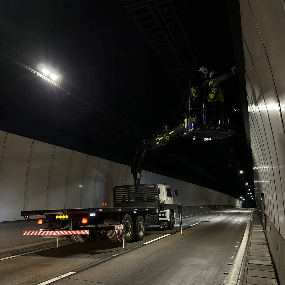 Operarios trabajando desde un canastillo en el techo de un túnel durante la noche